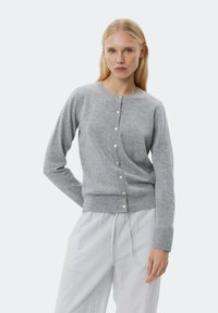 Grå cardigan i mjukt material, med rund hals, knappknäppning och ribbat avslut. Matcher med randiga byxor.