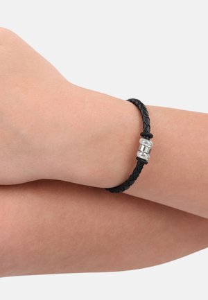 Schwarzes, geflochtenes Lederarmband mit einem metallischen Silberverschluss und einem schlanken, zylindrischen Design. Die strukturierte Oberfläche verleiht dem Armband zusätzliche Details.