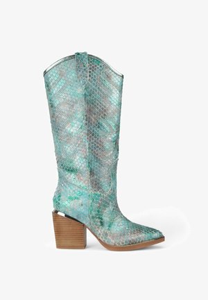 Bota de vaquero azul claro y con patrón de serpiente plateada, con punta afilada, un tacón de madera gruesa y un borde superior metálico suave.