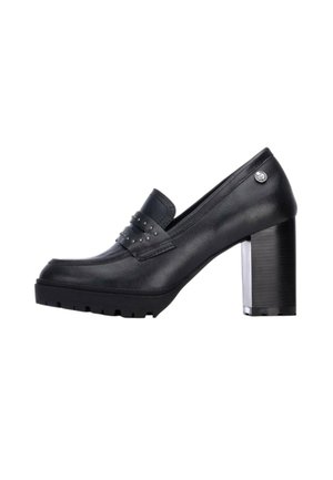 Mocasín de cuero negro con tacón alto, detalle de correa con tachuelas y tacón grueso, mostrado de lado sobre un fondo blanco.