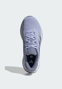 Chaussure de sport violet pâle avec une tige en mesh, accents blancs et bandes grises. Présente un design à lacets et une semelle extérieure texturée pour l'adhérence.