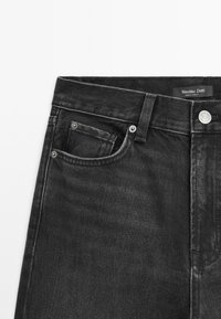 Zwarte denim jeans met een hoge taille, voorzak, zilverkleurige details en contrasterend stiksel. Label leest "Massimo Dutti."