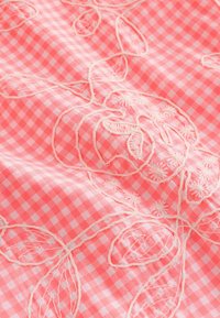 Rosa og hvid tjekket stof med hævet hvid blomsterbroderi med roser og blade.