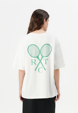 White cotton t-shirt featuring green graphic design of crossed tennis rackets and letters "R T C" on the back; short sleeves, relaxed fit.