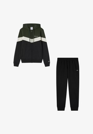 Felpa con cappuccio grigia scura, verde e bianca, con tasche laterali. Abbinata a pantaloni della tuta neri con vita elasticizzata.