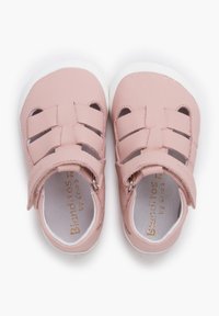 Sandalias de cuero rosa con diseño de punta cerrada, que presentan correas cruzadas y un cierre de velcro, montadas sobre una suela de goma blanca.