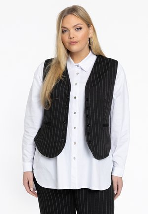 Zwarte pinstripe gilet met een op maat gemaakte uitstraling, voorzien van een geknipte kraag, voor knopen en twee zijzakken; gedragen over een wit shirt.