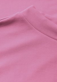 Světle růžová bavlněná látka s hladkým povrchem, s kulatým výstřihem a krátkými rukávy. Jemné prošívání okolo švů.