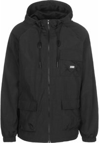 Veste noire à capuche avec fermeture éclair à l'avant, cordons, poignets élastiques et trois poches à rabat dont une avec le logo "Urban Classics".