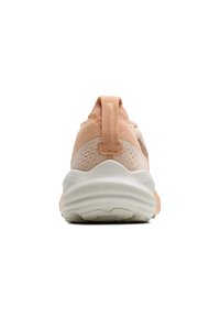 Light peach athletic shoe with a textured upper, padded heel tab, and white sole featuring a ripple design.