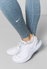 Niebo niebieskie legginsy heathered w połączeniu z białymi butami sportowymi z jasnoniebieskim akcentem i widocznym brandingiem po bokach oraz na języku.