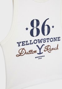 Witte tanktop met marineblauwe en bruine borduursels. Bevat de nummers "86," de tekst "YELLOWSTONE Dutton Ranch," en "MONTANA USA."