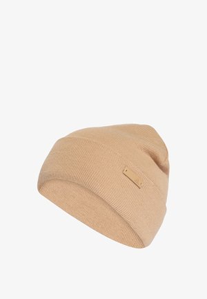 Bonnet en tricot beige avec une finition texturée. Présente une petite étiquette logo rectangulaire sur le côté. Matériau doux et flexible, forme ronde classique.