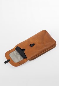 Braune Leder-Tasche, teilweise geöffnet, mit einem schwarzen Smartphone darin, zeigt gestreiftes Stofffutter und schwarzen Verschluss vor weißem Hintergrund.