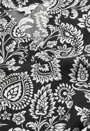 Sort stof med indviklede hvide blomster- og paisleymønstre, med V-hals og en synlig CELLEBES of Sweden mærkat i størrelse 38/40.