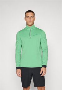 Grünes langärmliges Sportoberteil mit einem Reißverschlusskragen, ausgestattet mit einem schwarzen Reißverschluss und Manschetten. Der Stoff wirkt glatt und hat eine körperbetonte Passform.