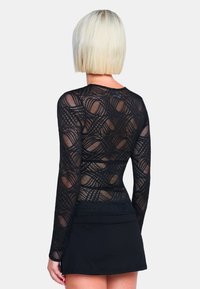 Schwarzes Longsleeve-Shirt mit einem gemusterten Mesh-Design und geschwungenen Linien, kombiniert mit einem einfarbigen schwarzen Rock. Glatte Textur, figurbetonte Passform.