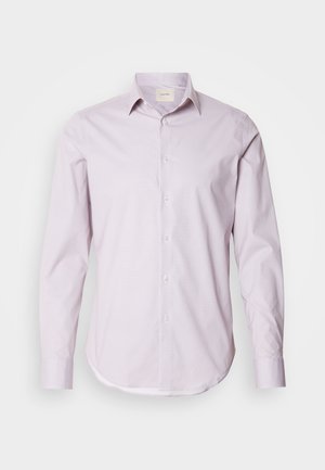 Camisa de manga larga de color rosa claro con pequeños lunares blancos, cuello abotonado y dobladillo redondeado. Fabricada con una tela suave y con un brillo sutil.