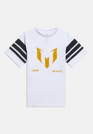 Valkoinen lyhythihainen T-paita, jonka hihoissa on mustat kaksoisraidat, keskellä oleva kultainen abstrakti tunnus ja sen alapuolella tekstit "LEGEND" sekä "THE G.O.A.T.".