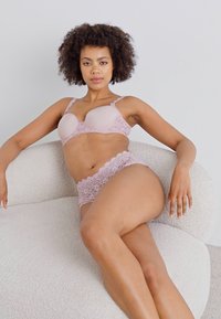 Light pink lingerie set featuring a molded cup bra and lace-trimmed panties; smooth texture with scalloped lace detailing.