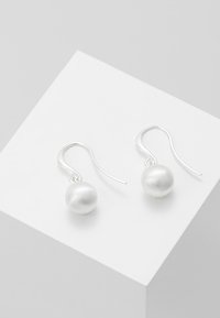 Silver hook earrings featuring large, matte finish white pearls hanging below. Simple and elegant design with no additional embellishments.