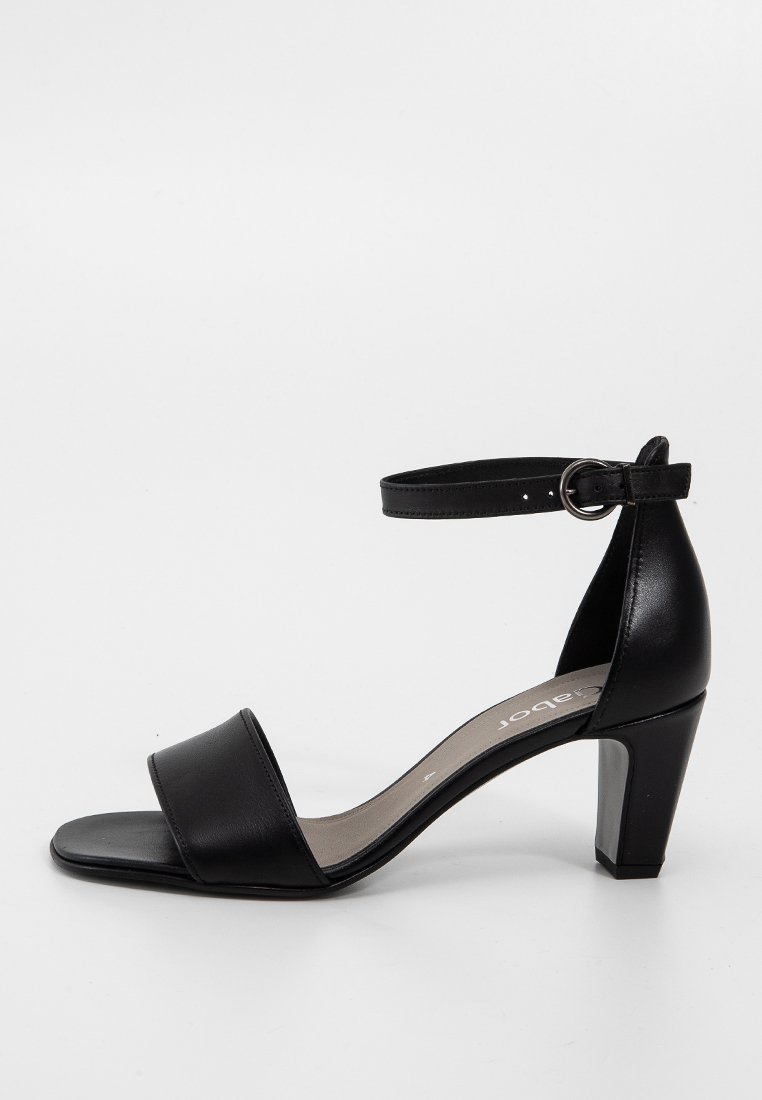Sandale en cuir noir avec une large bride sur le pied et une sangle ajustable à la cheville. Dispose d'un talon carré de hauteur moyenne.