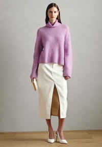 Suéter de punto lila con cuello alto ancho, combinado con una falda lápiz crema con una abertura frontal y tacones blancos de punta.