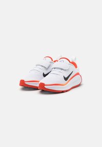 Witte sportieve schoenen met een bovenwerk van mesh, rode accenten, zwart swoosh-logo en klittenbandsluitingen. Lichtgewicht ontwerp met gevoerde zolen.