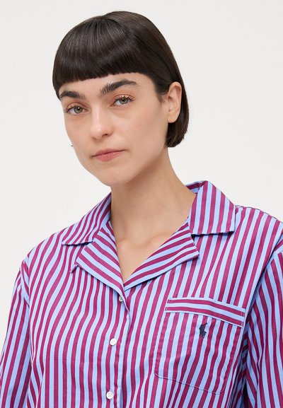 Cămașă de pijama din bumbac, cu dungi verticale alternate în nuanțe de purpuriu și albastru deschis, o buzunar pentru piept și un guler cu tăietură și închidere cu nasture.