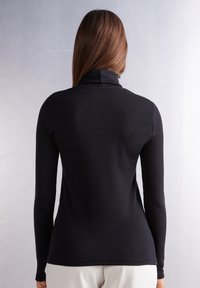 Col roulé noir à manches longues en tissu lisse et extensible ; coupe ajustée avec un col haut et aucune couture visible à l'arrière.