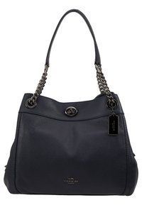 Sac à main Coach en cuir noir avec chaîne et bandoulière en cuir, fermeture à tourniquet et étiquette de marque sur le côté droit.