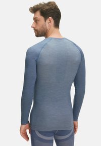 Camicia blu a maniche lunghe con pannelli in rete testurizzati sulla schiena e sulle spalle, design aderente e finitura in tessuto liscia.