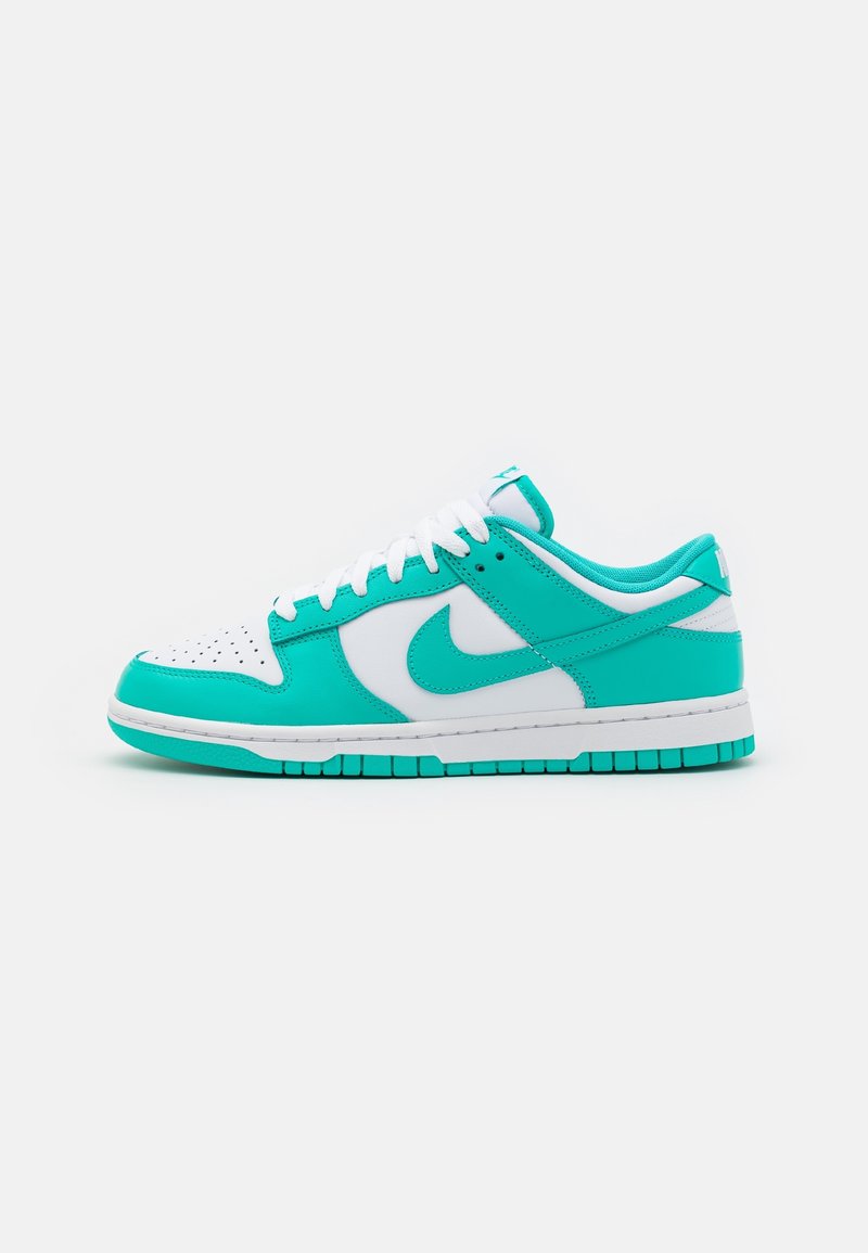 Baskets basses avec base blanche et surpiqûres turquoise, lacets blancs et logo Nike swoosh turquoise sur le côté.