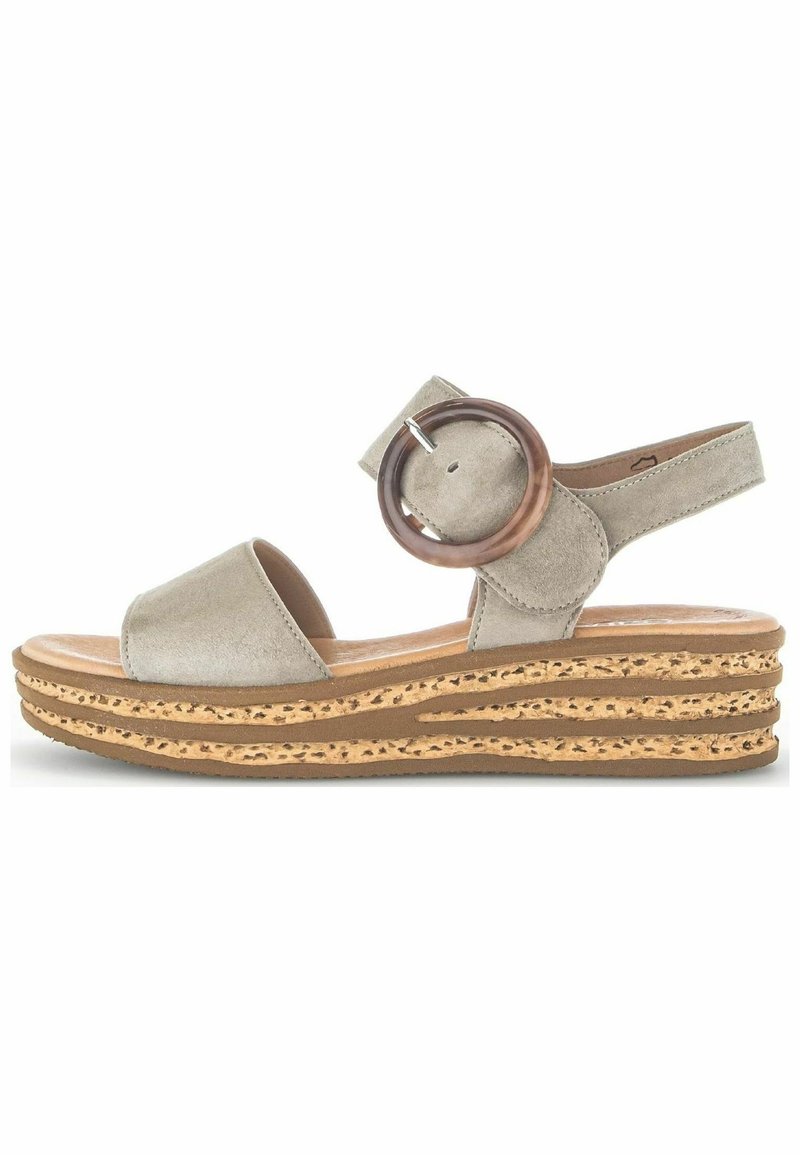 Sandale compensée beige à bout ouvert avec une semelle épaisse à motif liège et une grande boucle ronde sur la bride de cheville.
