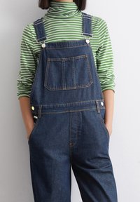 Džínové lacláče s nastavovacími popruhy, přední kapsou a bočními knoflíky. V kombinaci se zeleno-bílým pruhovaným rolákem. Hladká textura.