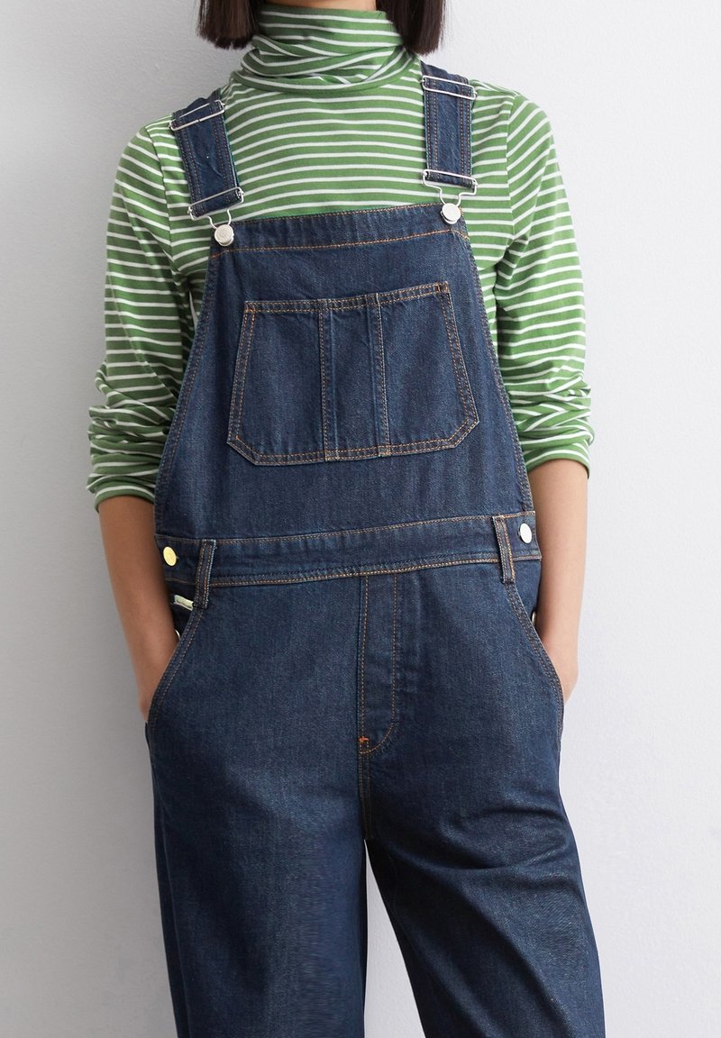 Džínové lacláče s nastavovacími popruhy, přední kapsou a bočními knoflíky. V kombinaci se zeleno-bílým pruhovaným rolákem. Hladká textura.