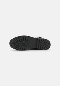 Czarna gumowa podeszwa z teksturowanym wzorem o wysokiej przyczepności, z okrągłymi i żłobionymi detalami dla lepszej trakcji i trwałości.