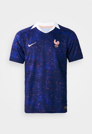Camiseta de fútbol azul marino con diseño texturizado, cuello blanco y emblema de gallo naranja. Presenta el logo de Nike y colores contrastantes.