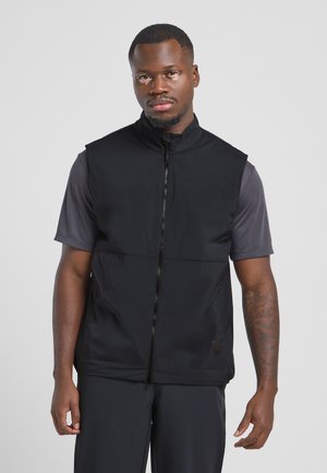 Black sleeveless vest with a high collar, front zipper, and two side pockets, made of lightweight, smooth fabric, paired with a dark gray shirt.