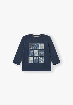 Camisa de manga larga azul marino con un diseño de cuadrícula de gráficos, que incluye texto y paisajes urbanos, en azul claro y blanco. Material de algodón suave.