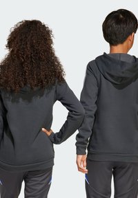 Sweat-shirts à capuche gris foncé avec poches kangourou, des poignets côtelés et un ourlet côtelé. Fabriqué en tissu doux et présente des accentuations contrastantes sur les manches.