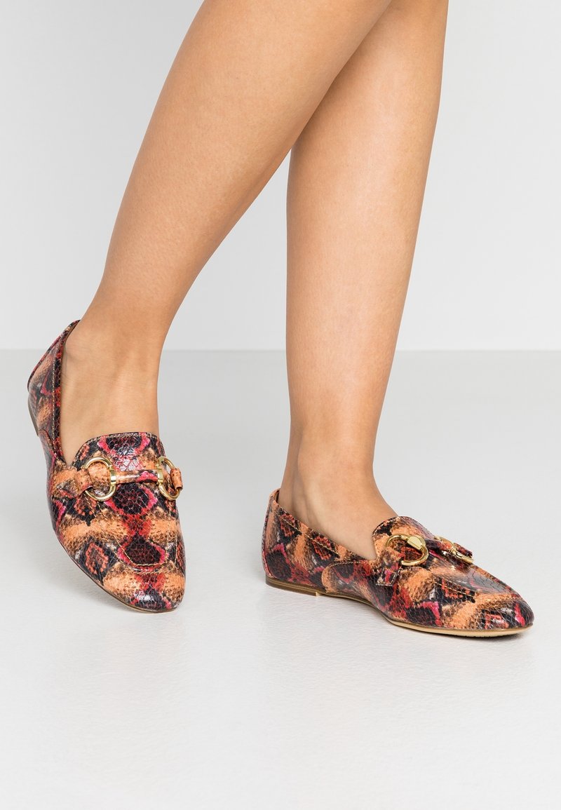 Chaussures plates avec un motif serpent multicolore, dotées d'un bout arrondi et d'accents en métal doré sur la tige. Texture lisse.