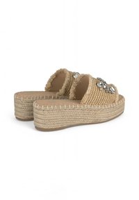 Sandales espadrilles tissées beiges avec un dessus texturé, des accents de pierres précieuses décoratives et une semelle plateforme en jute surélevée.