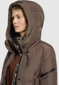 Bruine geïsoleerde zip-up jas met een grote capuchon, voorzien van een getextureerd oppervlak, trekkoorden en een zijvak met rits.