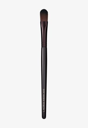 Pinceau de maquillage à manche noir avec des poils denses et arrondis et la marque Laura Mercier imprimée sur le manche, présenté sur un fond uni.