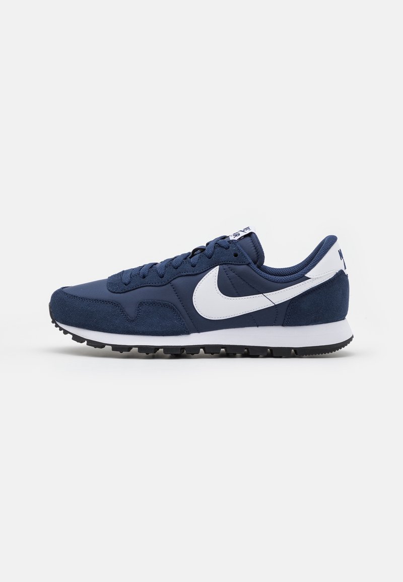 Chaussure de running Nike bleu marine et blanche avec des détails en suède et en tissu, logo swoosh blanc et semelle en caoutchouc noire, vue de côté.