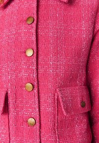 Wolmix jas in levendig roze met een gestructureerd patroon, voorzien van twee voorzakken en ronde goudkleurige knopen.