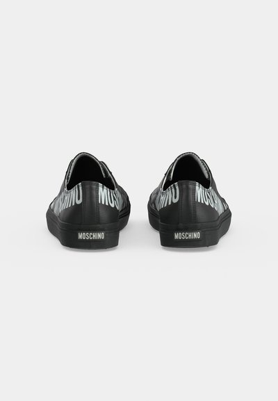 Paire de baskets basses noires avec le logo blanc MOSCHINO au dos et sur les côtés, sur fond blanc.