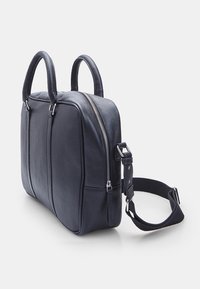 Sort lædertaske med dobbelte hanke og justerbar rem. Har en toplynlås, tekstureret overflade og to sidelommer til opbevaring.