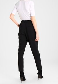 Czarne eleganckie spodnie z dopasowanym pasem, prostymi nogawkami i tylnymi kieszeniami. Połączone z bluzką z krótkim rękawem w jasnoszarym kolorze oraz wysokimi botkami.